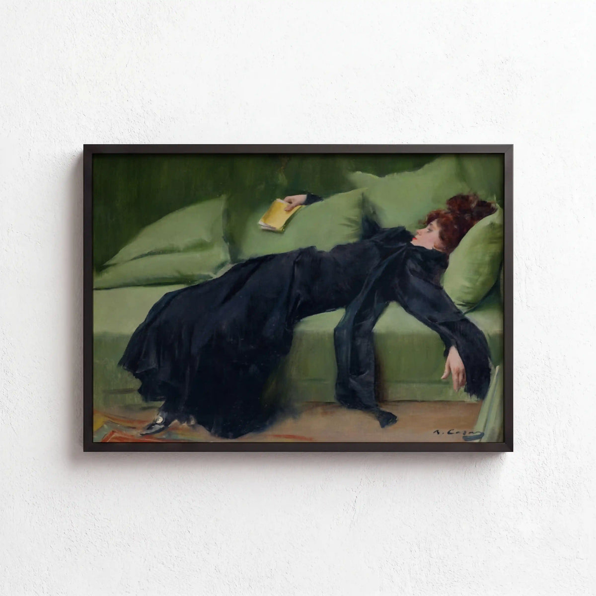 A framed art print depicting a woman in a long black dress reclining on a green sofa, hung on a textured white wall.